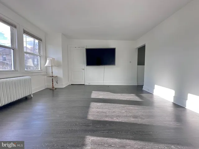 a view of empty room with window and wooden floor