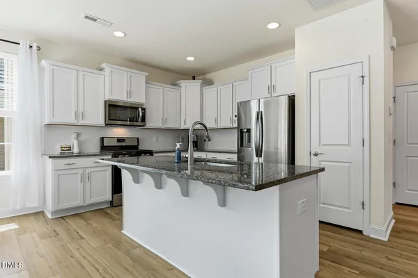 a kitchen with kitchen island a counter top space stainless steel appliances and cabinets