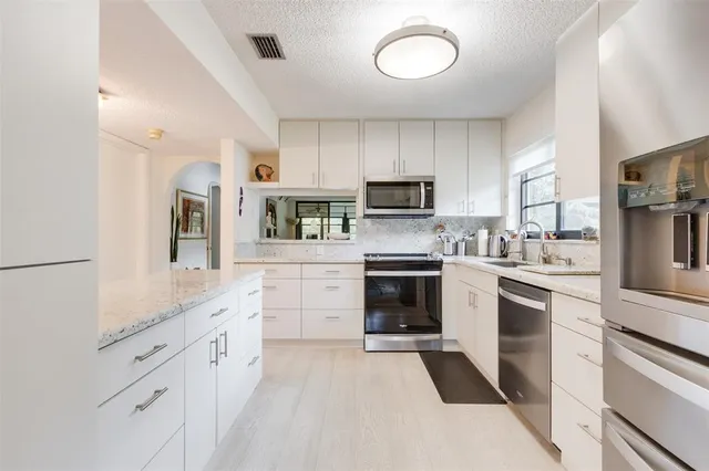 a kitchen with cabinets stainless steel appliances and sink