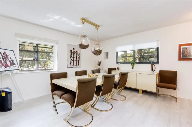 a dining room with wooden floor a chandelier a wooden table and chairs