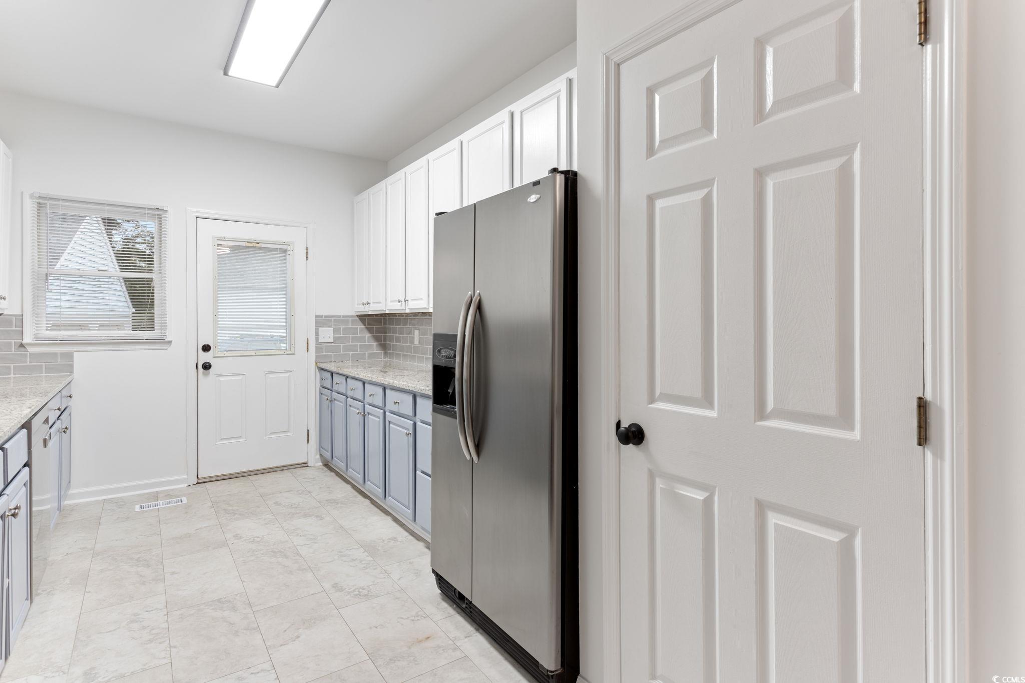 2321 Brick Drive Longs, SC 29568 - Photo 18 of 40 Kitchen with stainless steel fridge with ice dispenser, tasteful backsplash, white cabinets, light stone counters, and blue cabinets