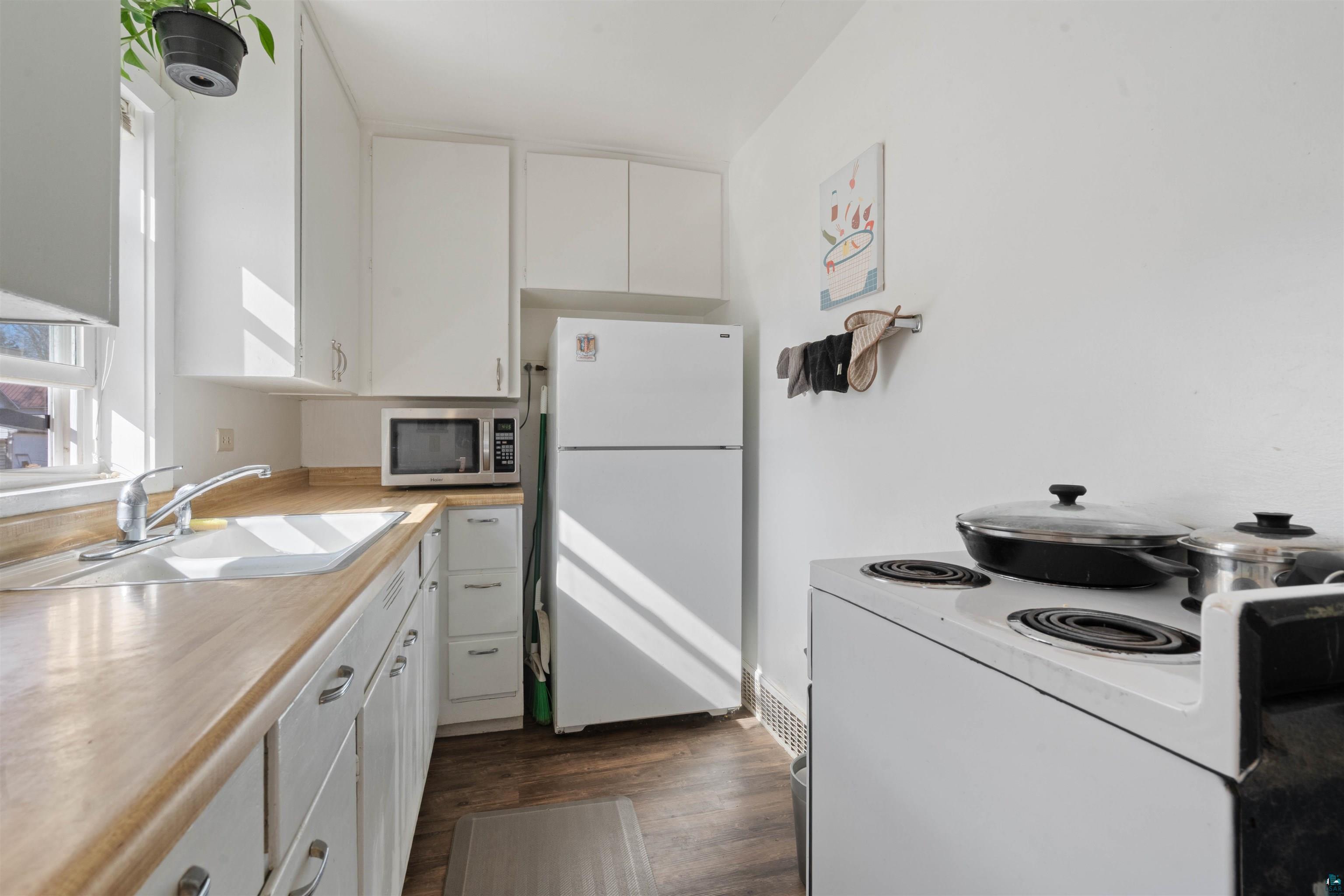 809 Prospect Avenue Cloquet, MN 55720 - Photo 11 of 20 Kitchen with white appliances, white cabinetry, light countertops, and dark wood-style flooring