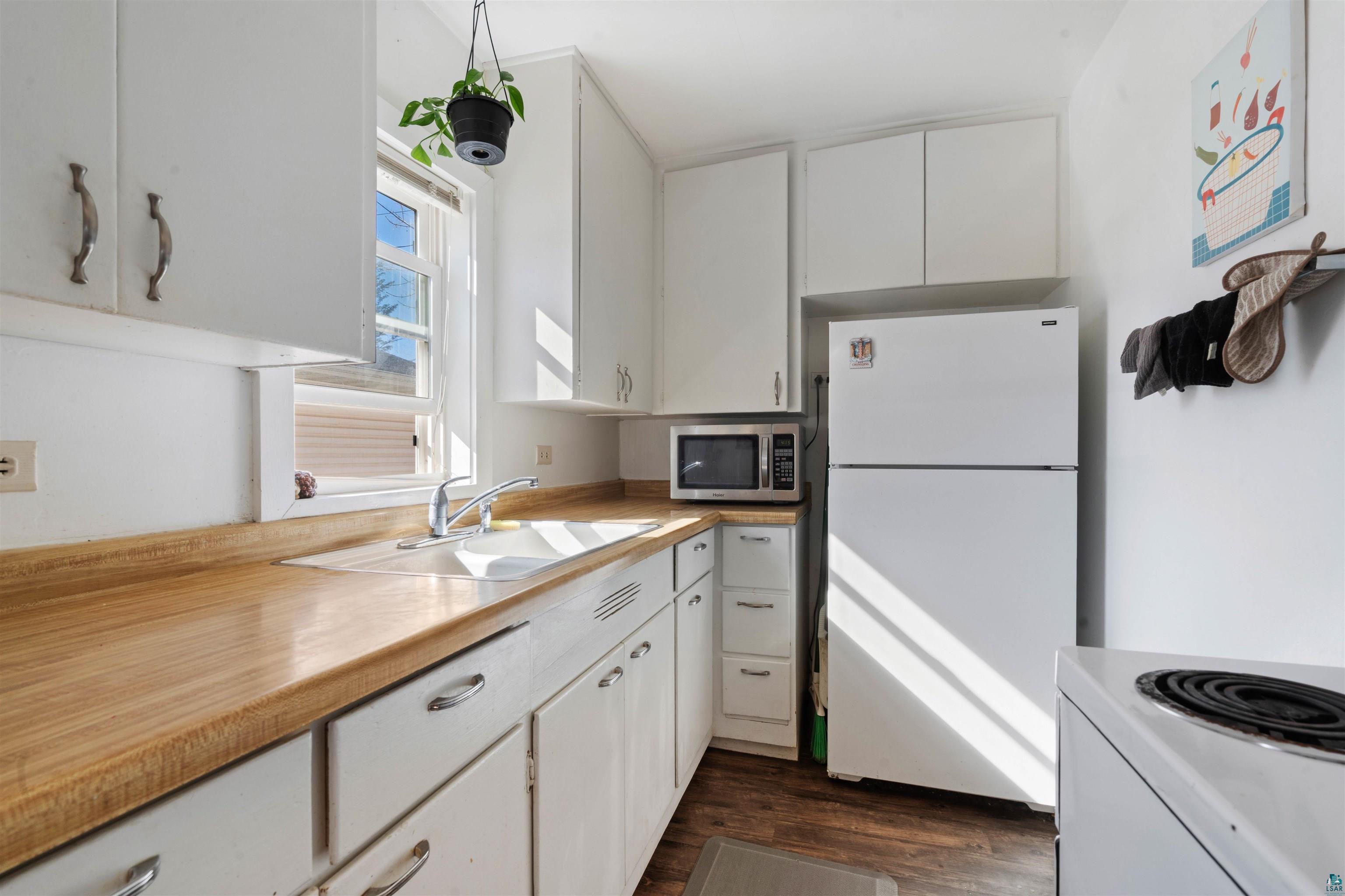 809 Prospect Avenue Cloquet, MN 55720 - Photo 12 of 20 Kitchen with white appliances, white cabinetry, light countertops, and dark wood-style flooring