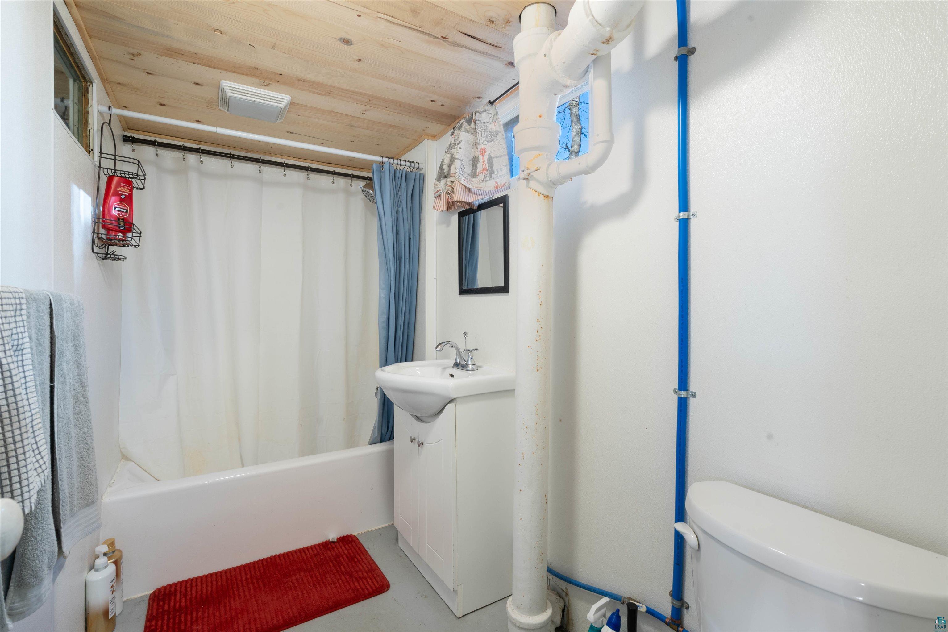 809 Prospect Avenue Cloquet, MN 55720 - Photo 15 of 20 Bathroom with vanity, shower / tub combo with curtain, wood ceiling, and concrete floors