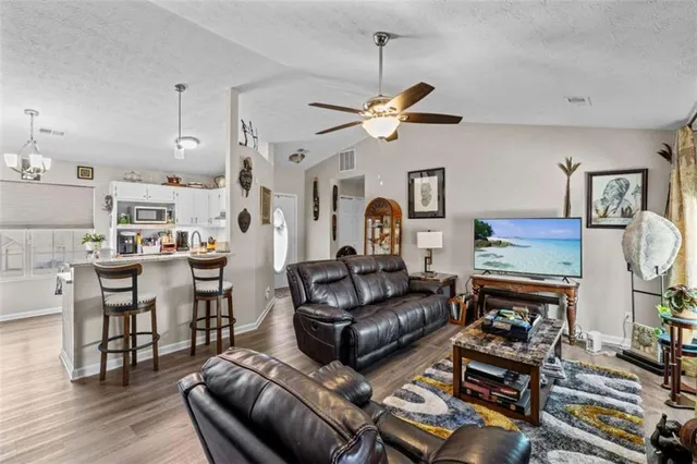 a living room with furniture kitchen view and a wooden floor