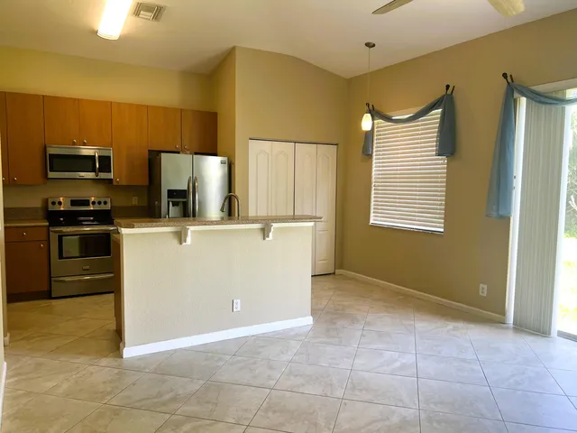 a kitchen with kitchen island a counter top space cabinets stainless steel appliances and a window