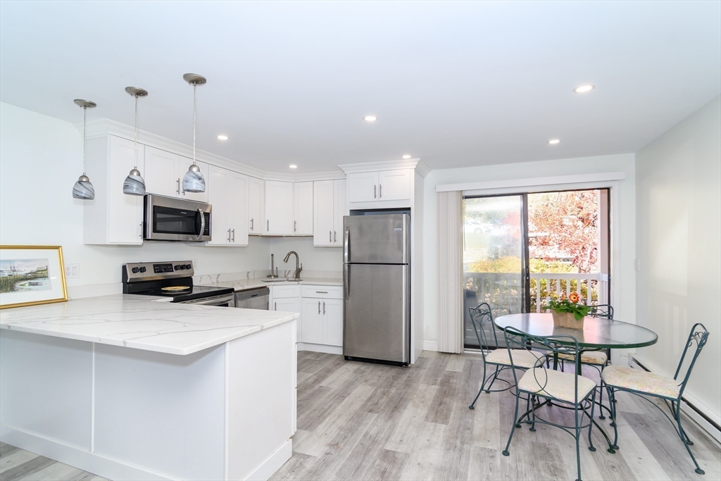 71 Edgeworth Street, Unit 21 Worcester, MA 01605 - Photo 2 of 13 a kitchen with stainless steel appliances a microwave a stove a refrigerator cabinets a dining table and chairs