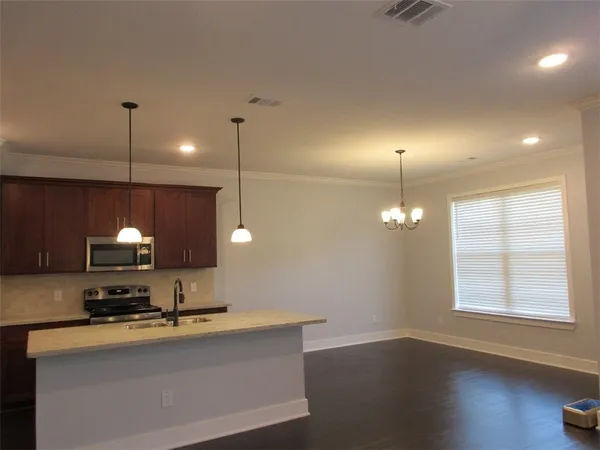 a open kitchen with kitchen island a sink stainless steel appliances and a chandelier