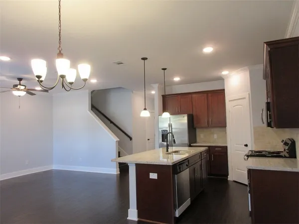 a kitchen with a sink a chandelier stainless steel appliances and cabinets