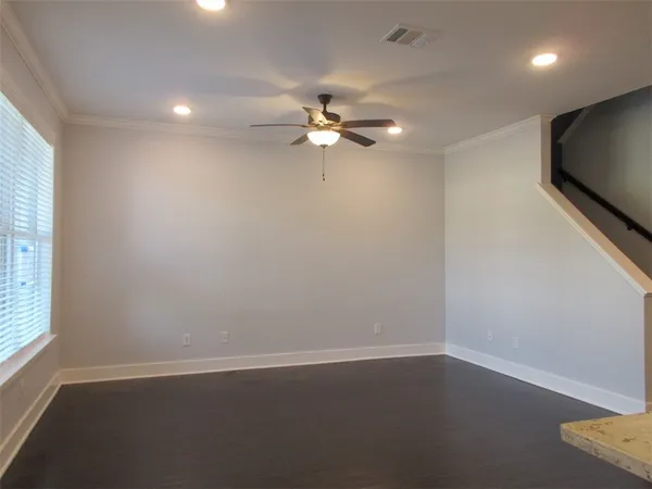 an empty room with wooden floor and fan