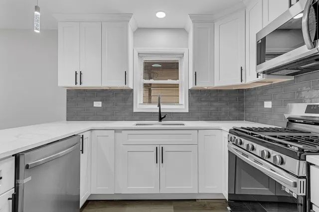 a kitchen with white cabinets and appliances