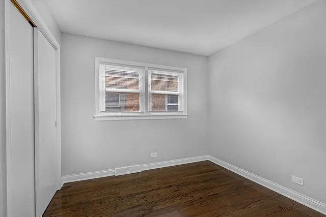 an empty room with wooden floor mirror and windows