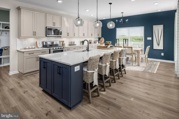 a kitchen with stainless steel appliances kitchen island granite countertop a table chairs sink and cabinets