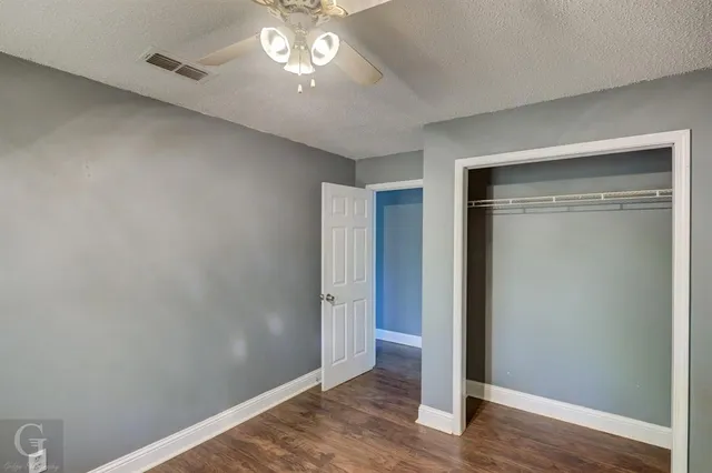 an empty room with wooden floor closet and windows