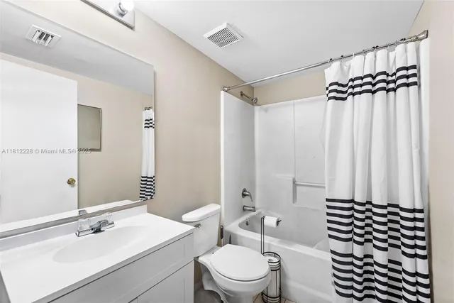 a bathroom with a sink a toilet a mirror and shower curtain