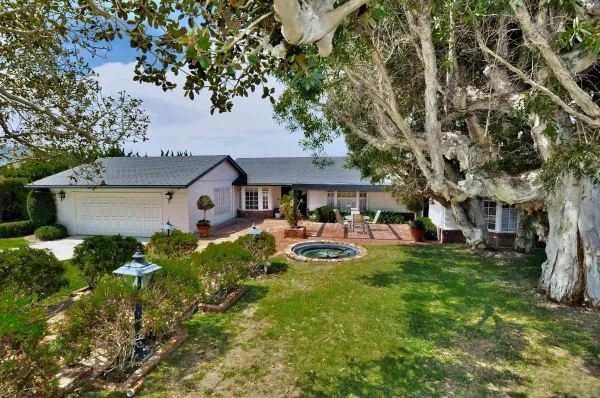 a front view of a house with garden and trees