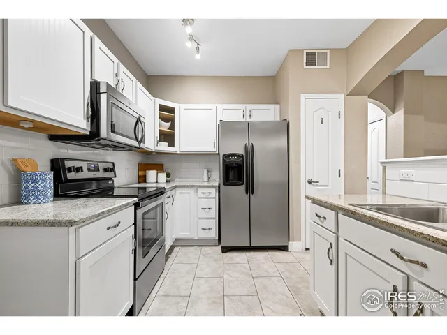 a kitchen with stainless steel appliances granite countertop a refrigerator a sink a stove and white cabinets