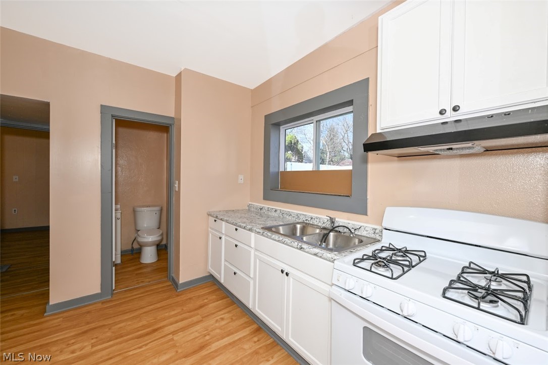 868 North Main Street Akron, OH 44310 - Photo 12 of 30 Kitchen with white gas range, white cabinets, and light wood-style floors