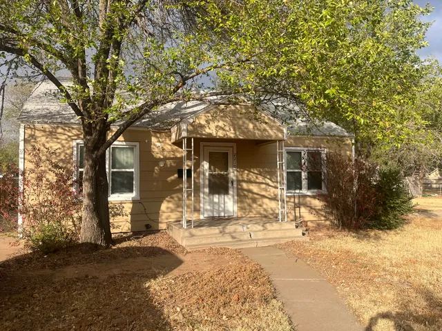 a front view of a house with a yard and large tree