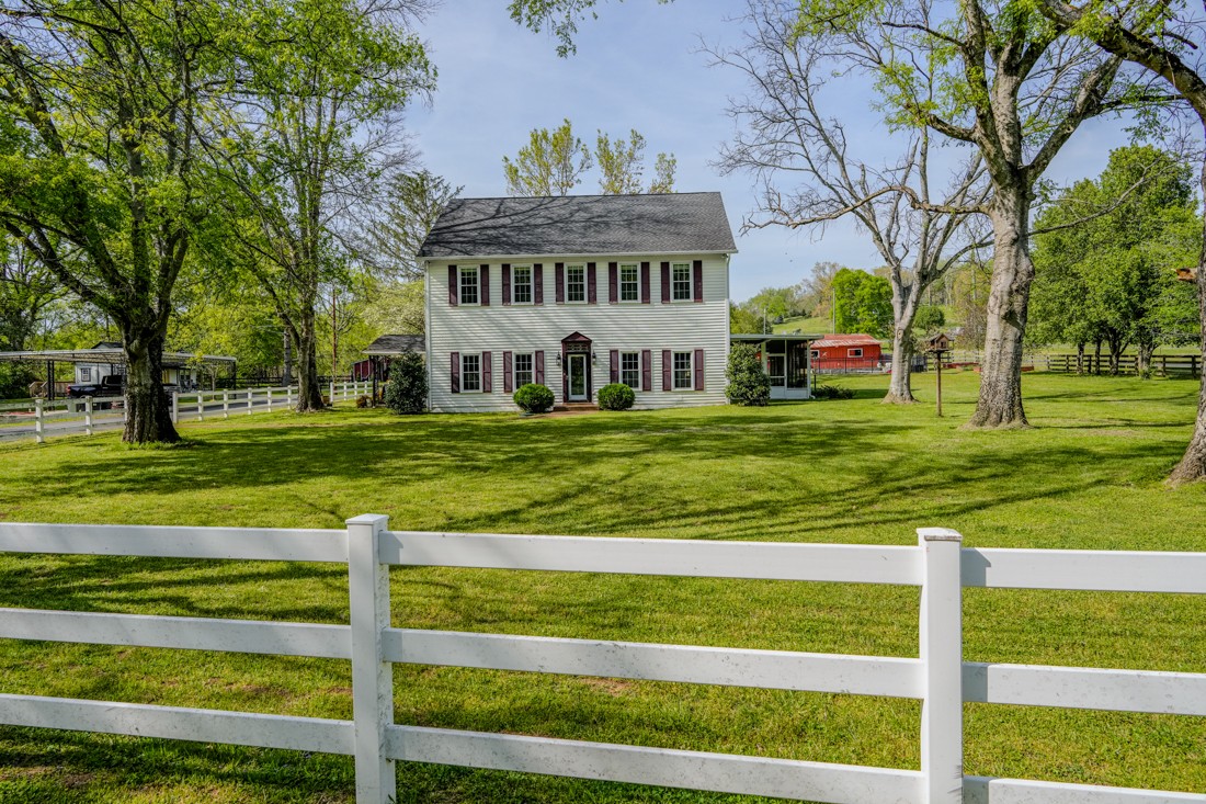 a view of a house with a big yard and large trees