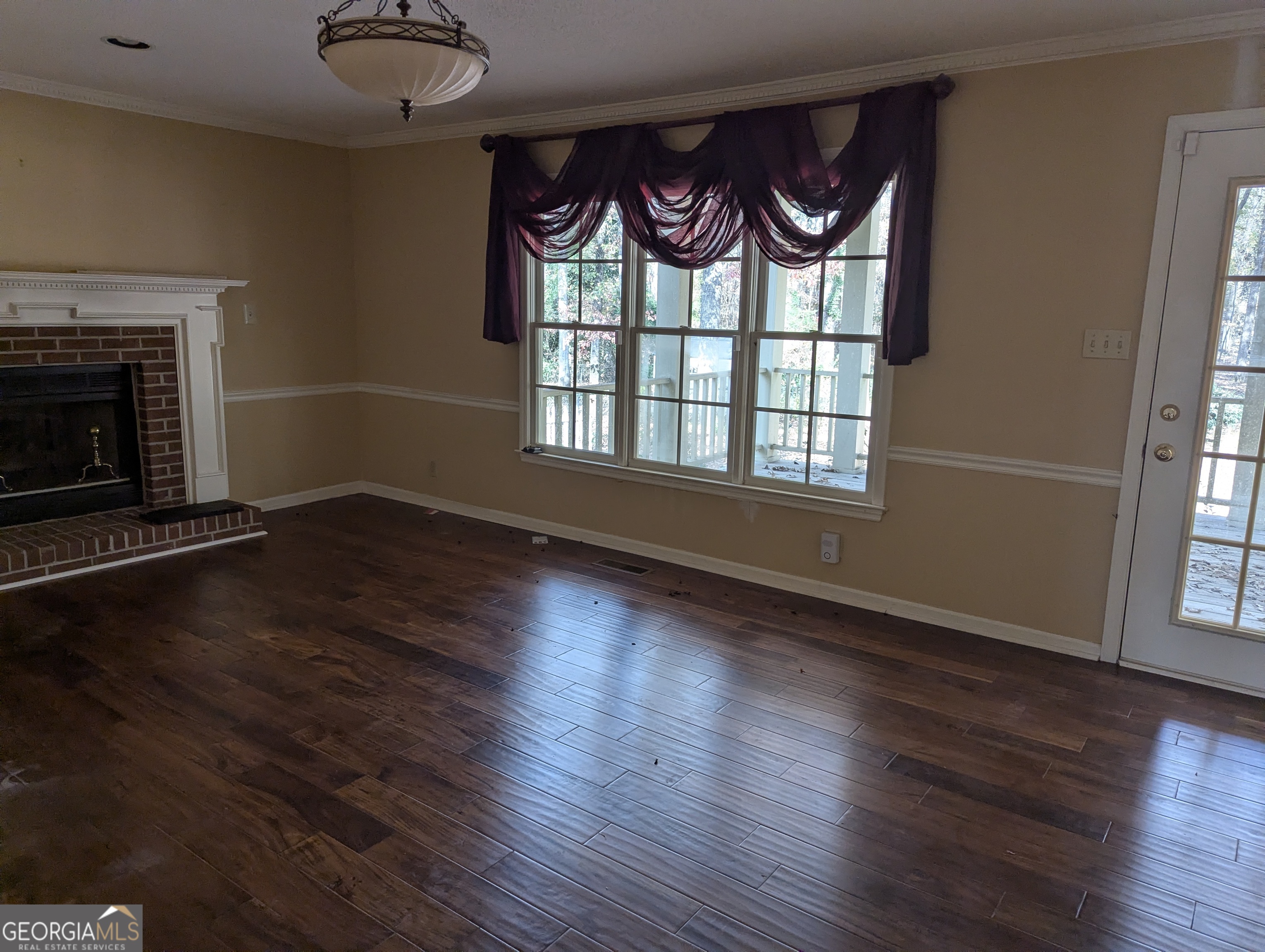 6111 Peake Road Macon, GA 31220 - Photo 4 of 21 an empty room with wooden floor fireplace and windows