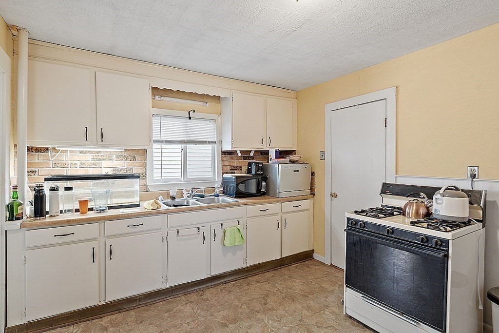 11 Autumn Street Lowell, MA 01852 - Photo 28 of 35 a kitchen with stainless steel appliances a sink stove and cabinets