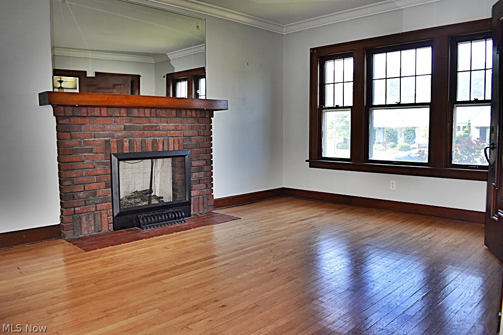 7715 Ackley Road Parma, OH 44129 - Photo 3 of 27 Unfurnished living room with ornamental molding, gleaming hardwood flooring, and a brick fireplace