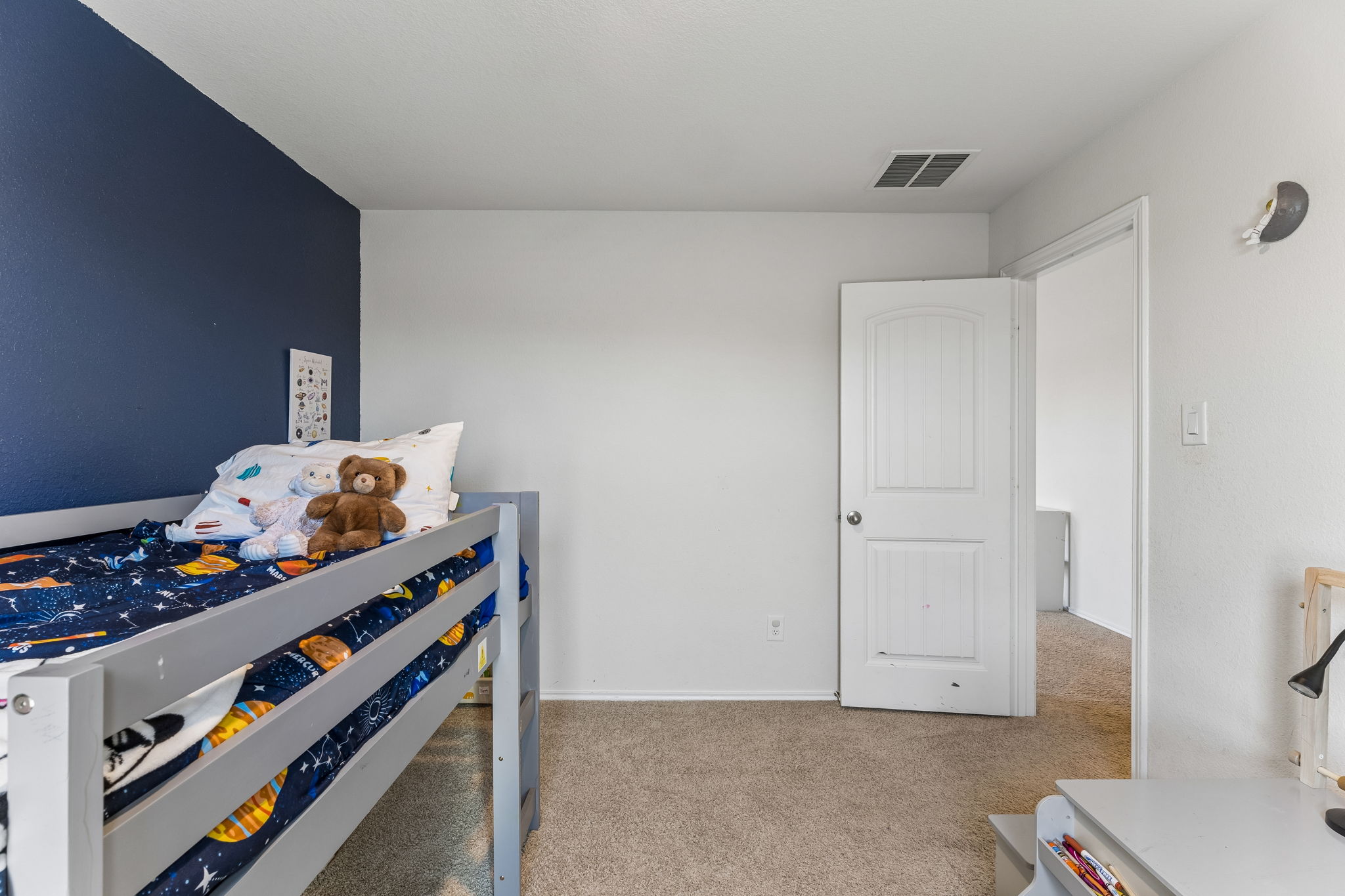 343 Sickle Loop Kyle, TX 78640 - Photo 29 of 40 Carpeted room featuring light gray walls, a contrasting dark blue accent wall, a white interior door with paneling, and an overhead ventilation register