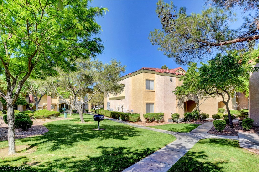 7885 West Flamingo Road, Unit 1050 Las Vegas, NV 89147 - Photo 57 of 62 Manicured green spaces and pathways connect charming stucco residential buildings under a bright sky.