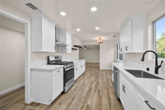 a large kitchen with stainless steel appliances granite countertop a lot of counter space and wooden floors