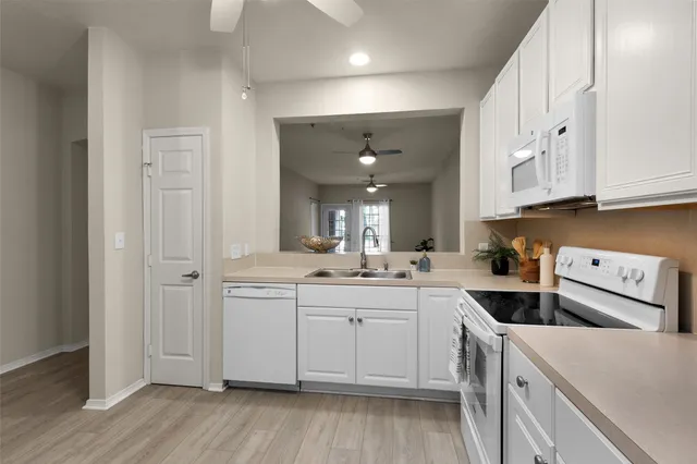 a kitchen with white cabinets white stainless steel appliances and sink