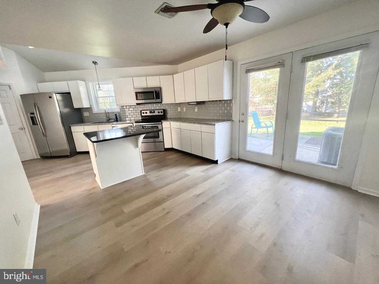 112 Spring Ridge Court Lancaster, PA 17601 - Photo 6 of 19 a kitchen with stainless steel appliances granite countertop a stove a refrigerator a sink a microwave a dining table and chairs with wooden floor