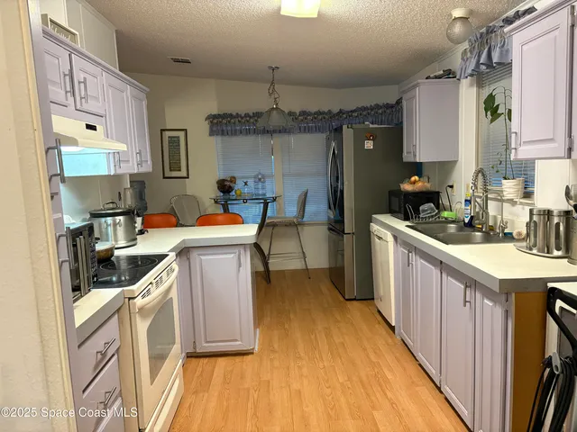 a kitchen that has a lot of cabinets in it and wooden floor
