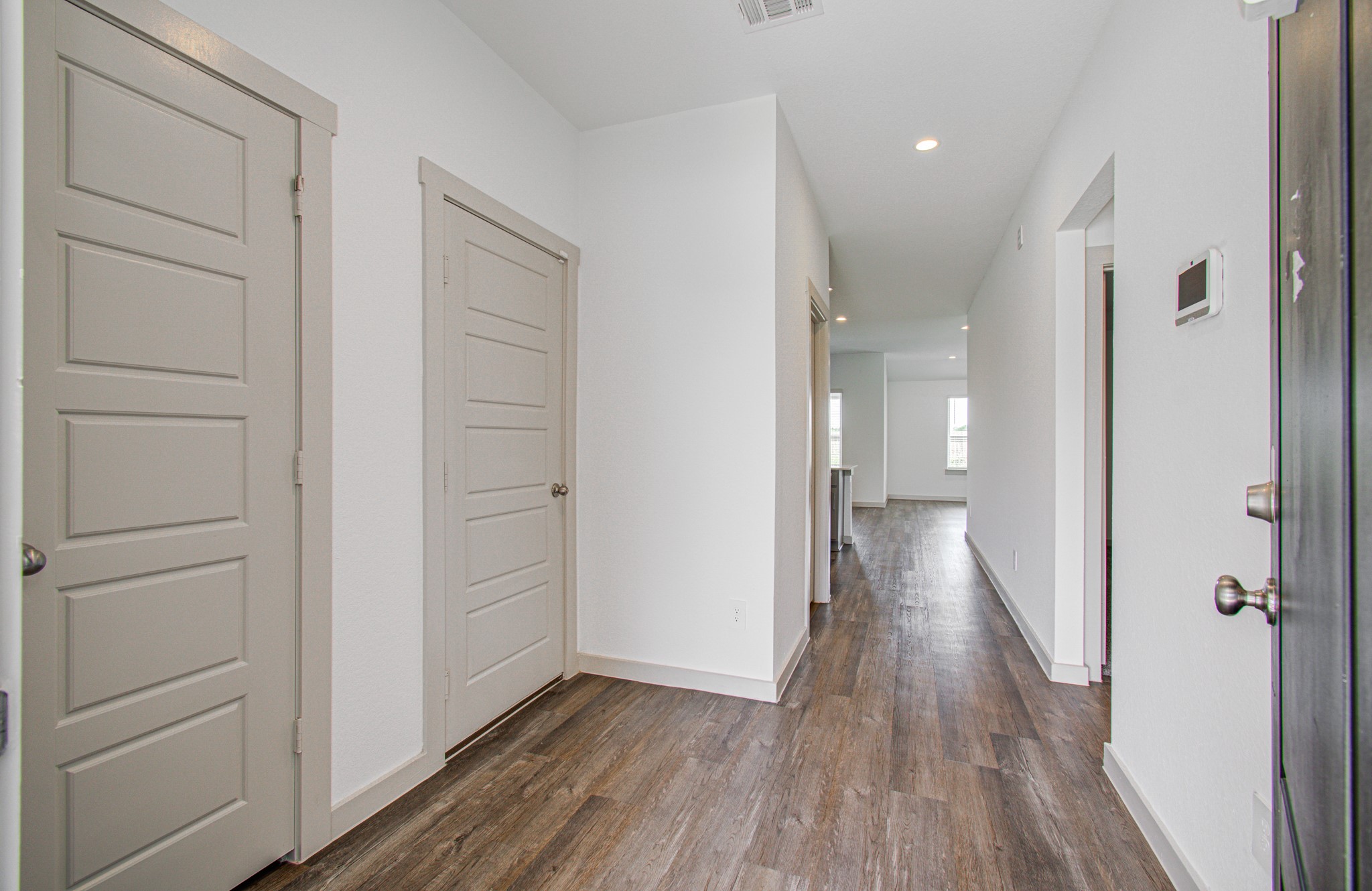 7903 Wrangler Shack Lane Rosharon, TX 77583 - Photo 5 of 29 This modern hallway, featuring elegant wood flooring and neutral-toned doors, is illuminated by recessed lighting and seamlessly leads into a bright, open living space, creating a warm and inviting entrance to your new home.