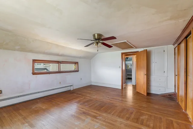 an empty room with wooden floor chandelier fan and windows
