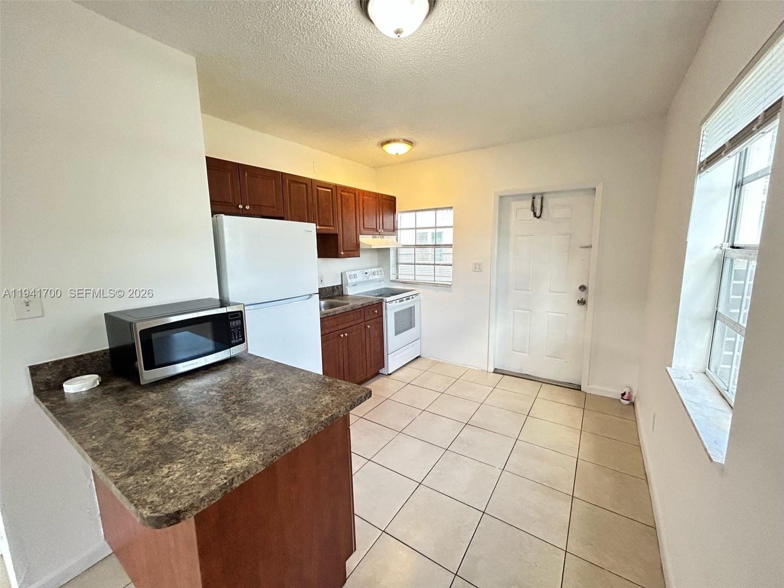 990 Phippen Waiters Road Dania Beach, FL 33004 - Photo 2 of 8 a kitchen with stainless steel appliances granite countertop a sink stove and refrigerator