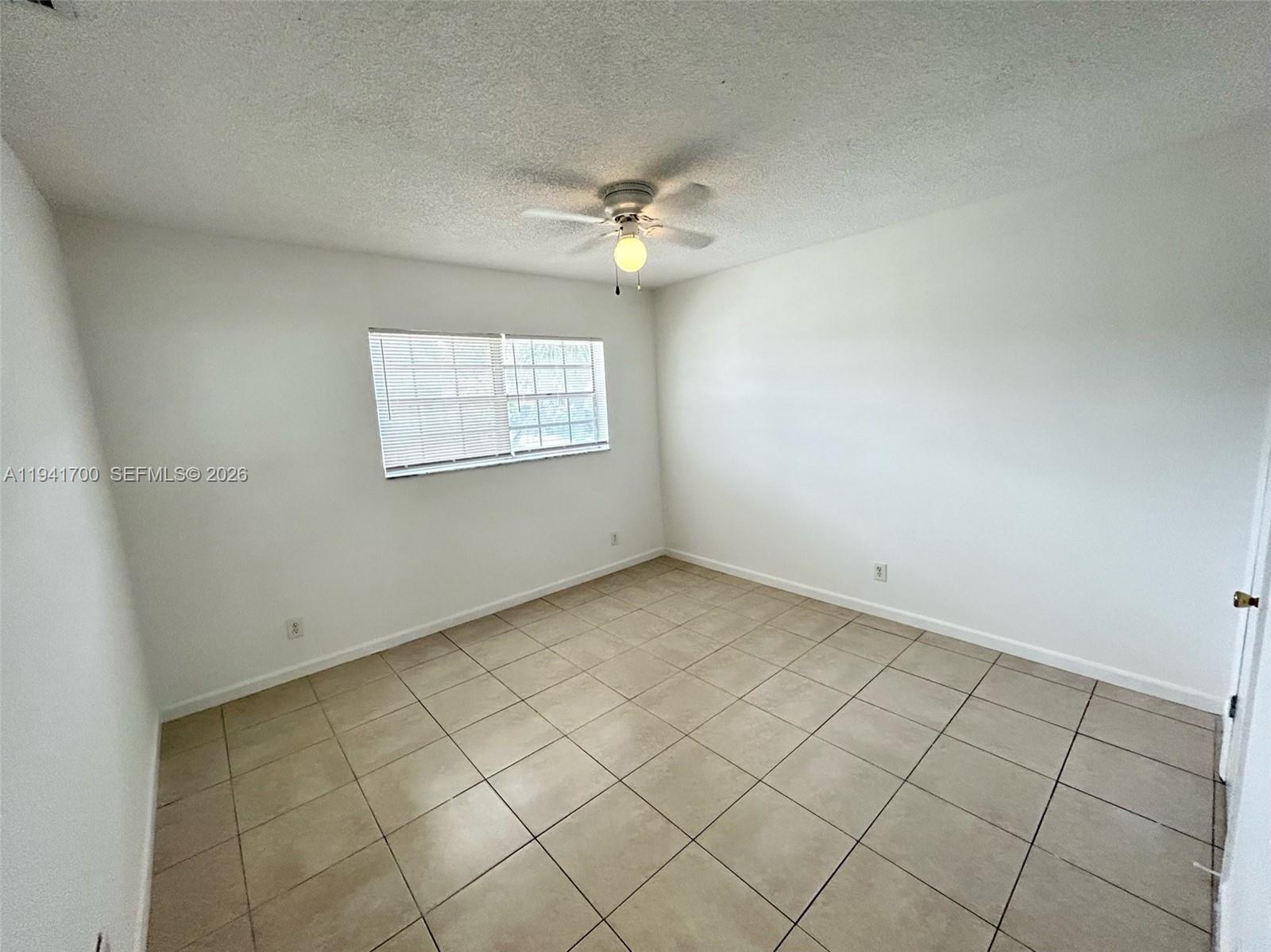 990 Phippen Waiters Road Dania Beach, FL 33004 - Photo 7 of 8 an empty room with windows and ceiling fan