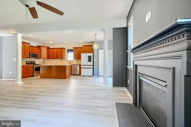 a view of a kitchen with a fridge wooden floor a ceiling fan and kitchen view
