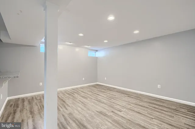 a view of an empty room with wooden floor and kitchen