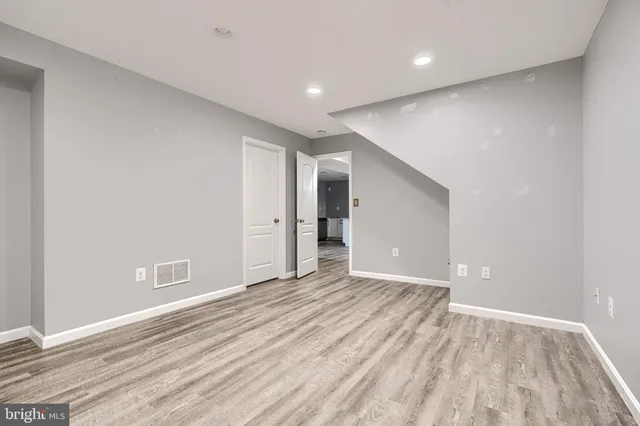 an empty room with wooden floor chandelier fan and windows