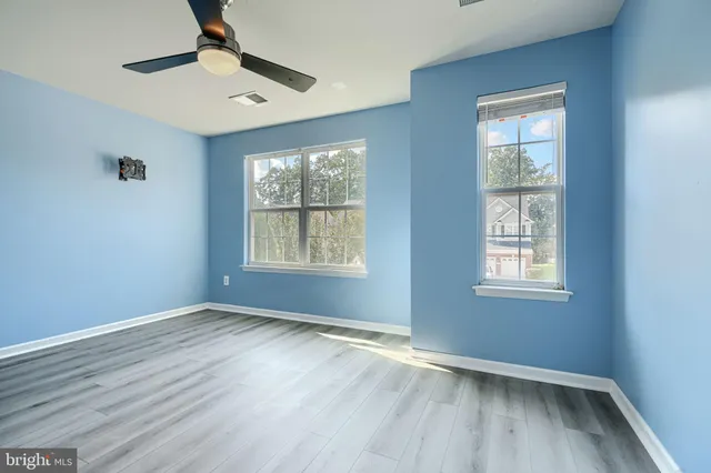 a view of an empty room with window and wooden floor