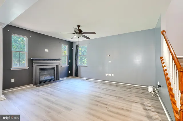 a view of an empty room with wooden floor and a ceiling fan