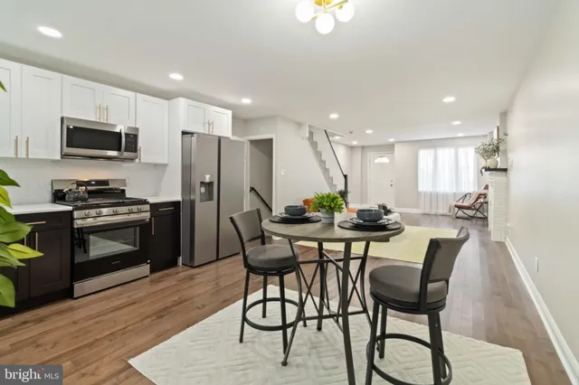 a kitchen with stainless steel appliances kitchen island granite countertop a refrigerator a stove a microwave oven a sink with island and chairs in it