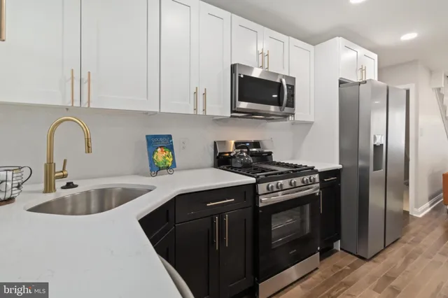 a kitchen with stainless steel appliances granite countertop a stove a sink dishwasher a refrigerator and a microwave oven with wooden floor