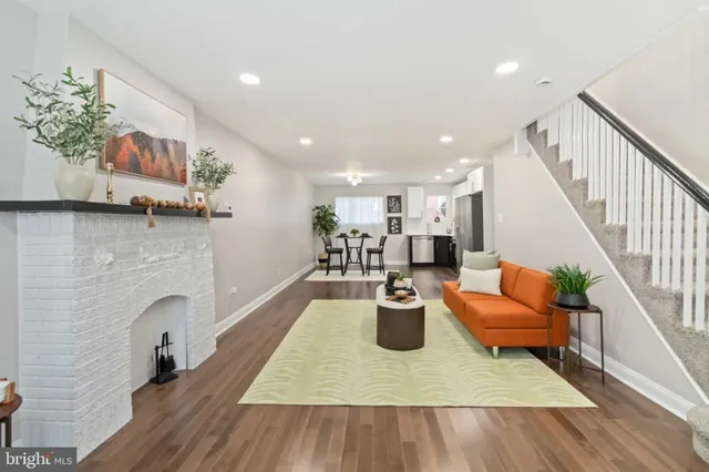 a living room with furniture kitchen view and a wooden floor