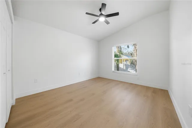 an empty room with windows and ceiling fan