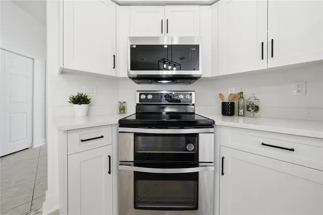 a kitchen with stainless steel appliances granite countertop white cabinets a stove a microwave and a refrigerator
