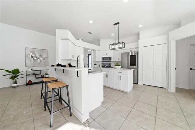 a kitchen that has a lot of white cabinets and stainless steel appliances