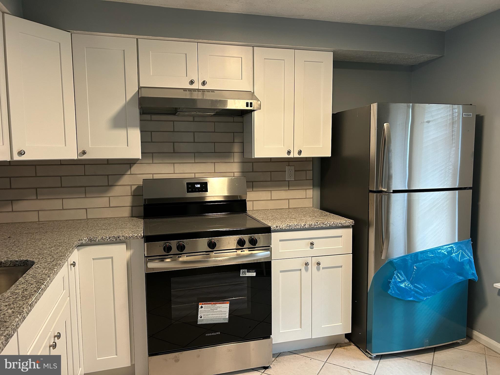 a kitchen with stainless steel appliances granite countertop a stove and a refrigerator