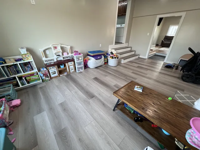 a view of a hallway to a livingroom with wooden floor and furniture